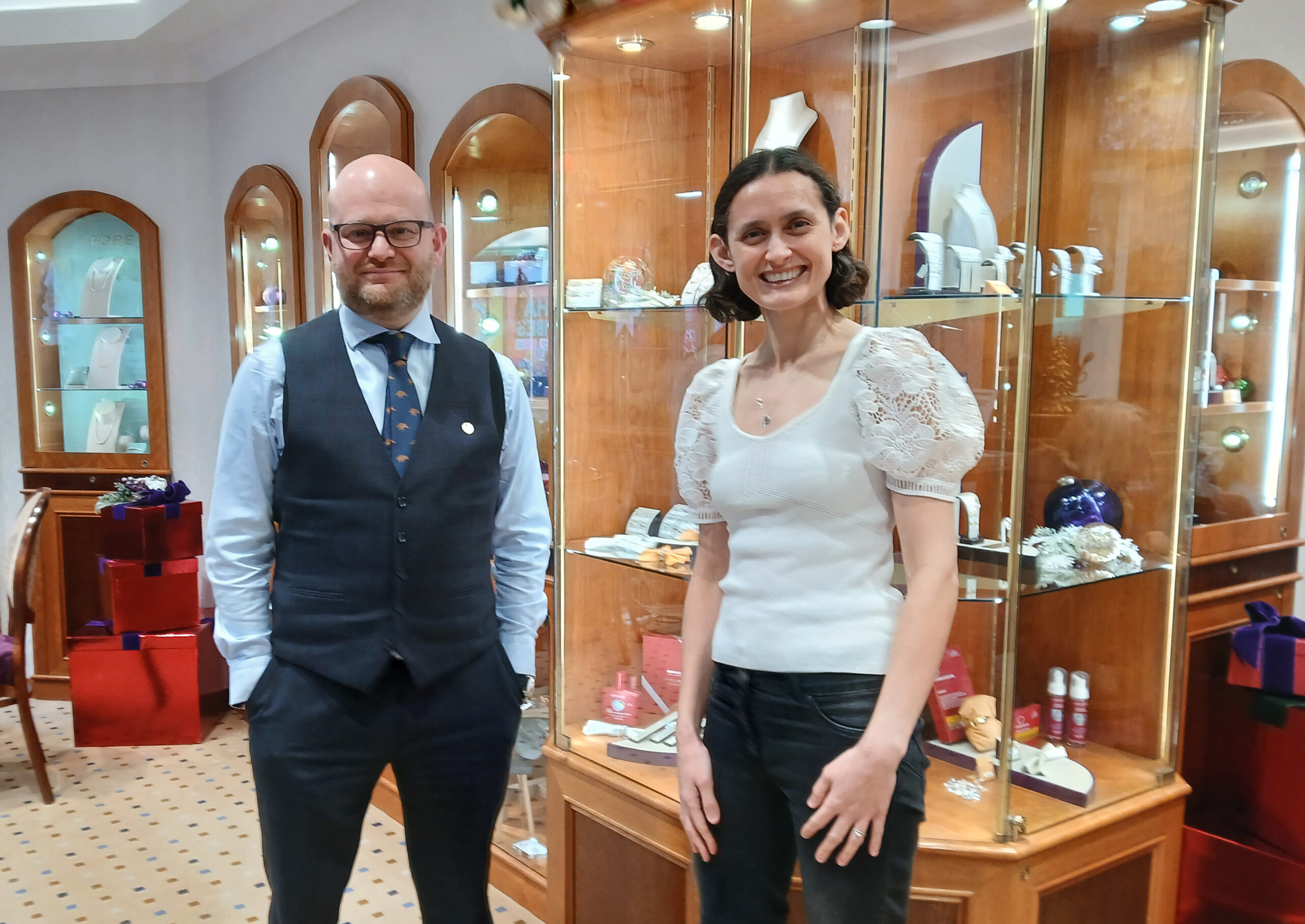 Maria Lloyd and Adam Jacobs standing in front of jewellery display at Jacobs Jewellers